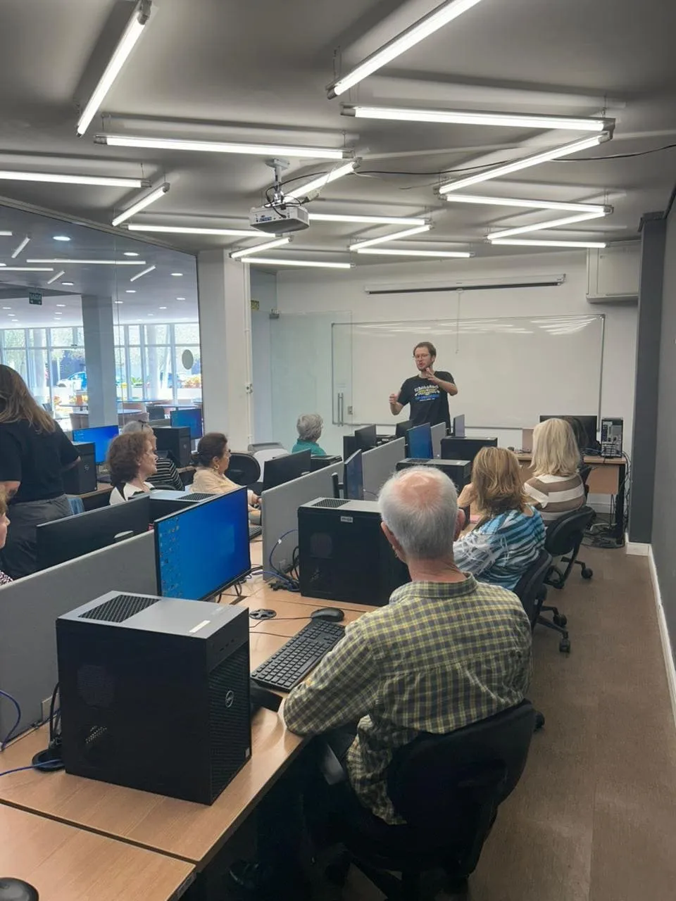 Alunos acompanham uma aula numa sala com computadores