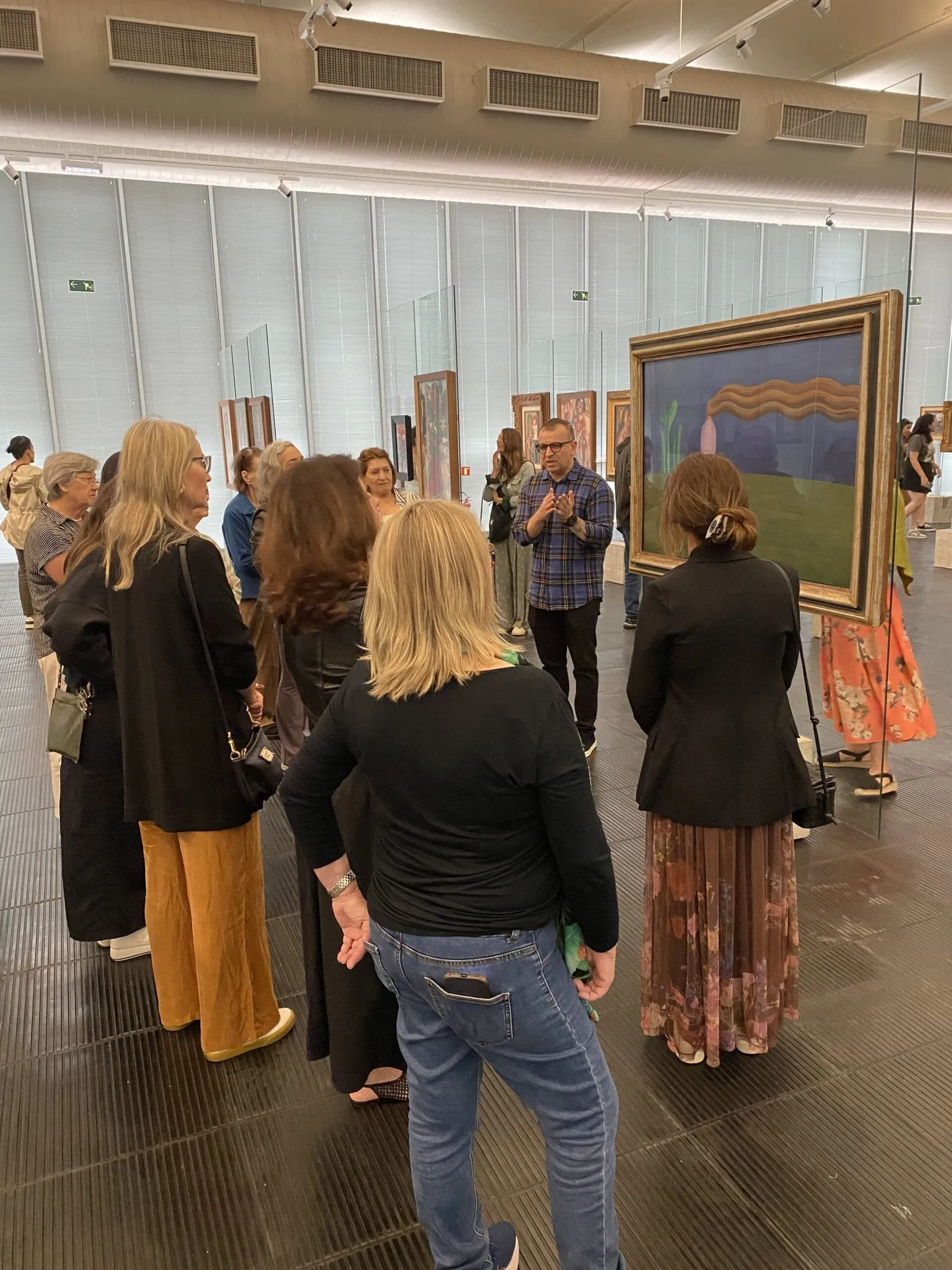 Grupo caminha por um salão de museu com pinturas emolduradas