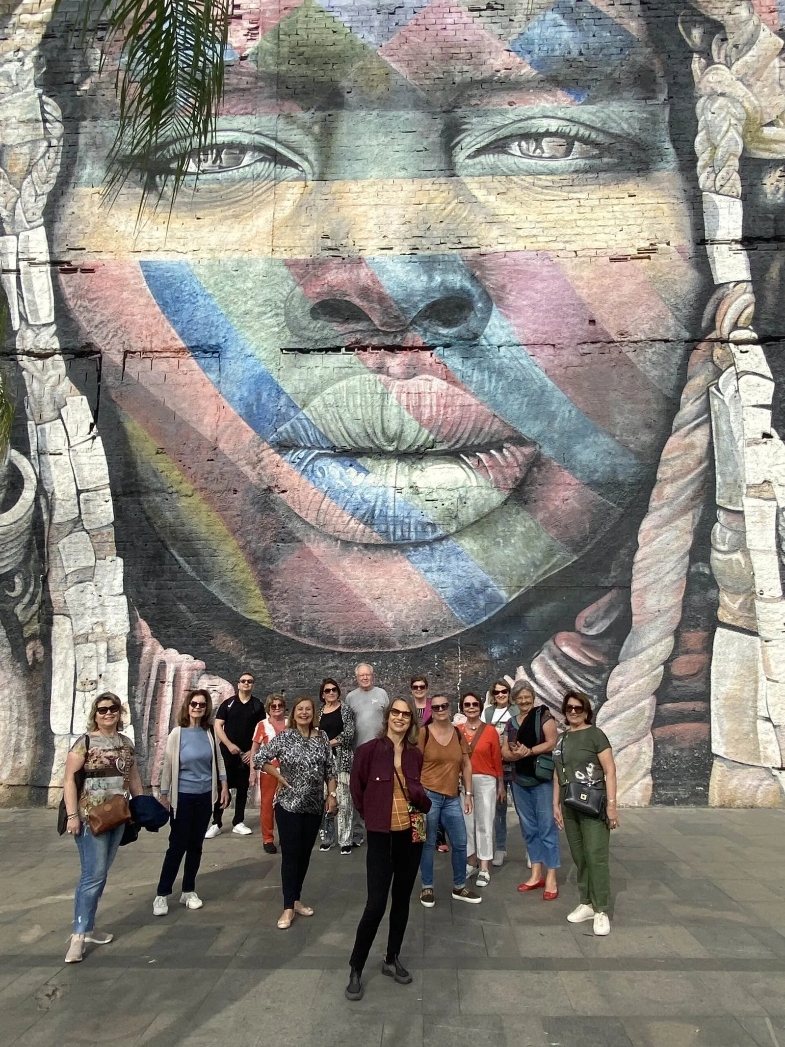 Grupo posa diante de um grande mural de arte urbana